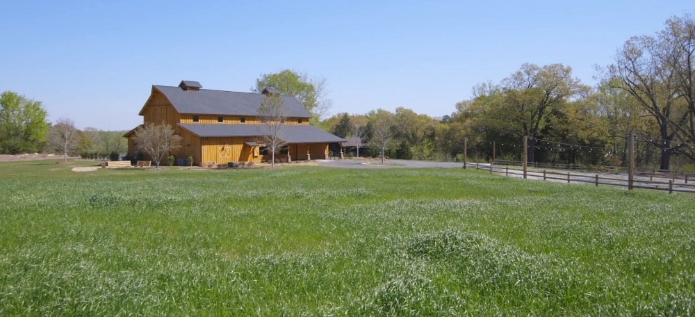windy hill barn wedding venue sits on the side of a green field