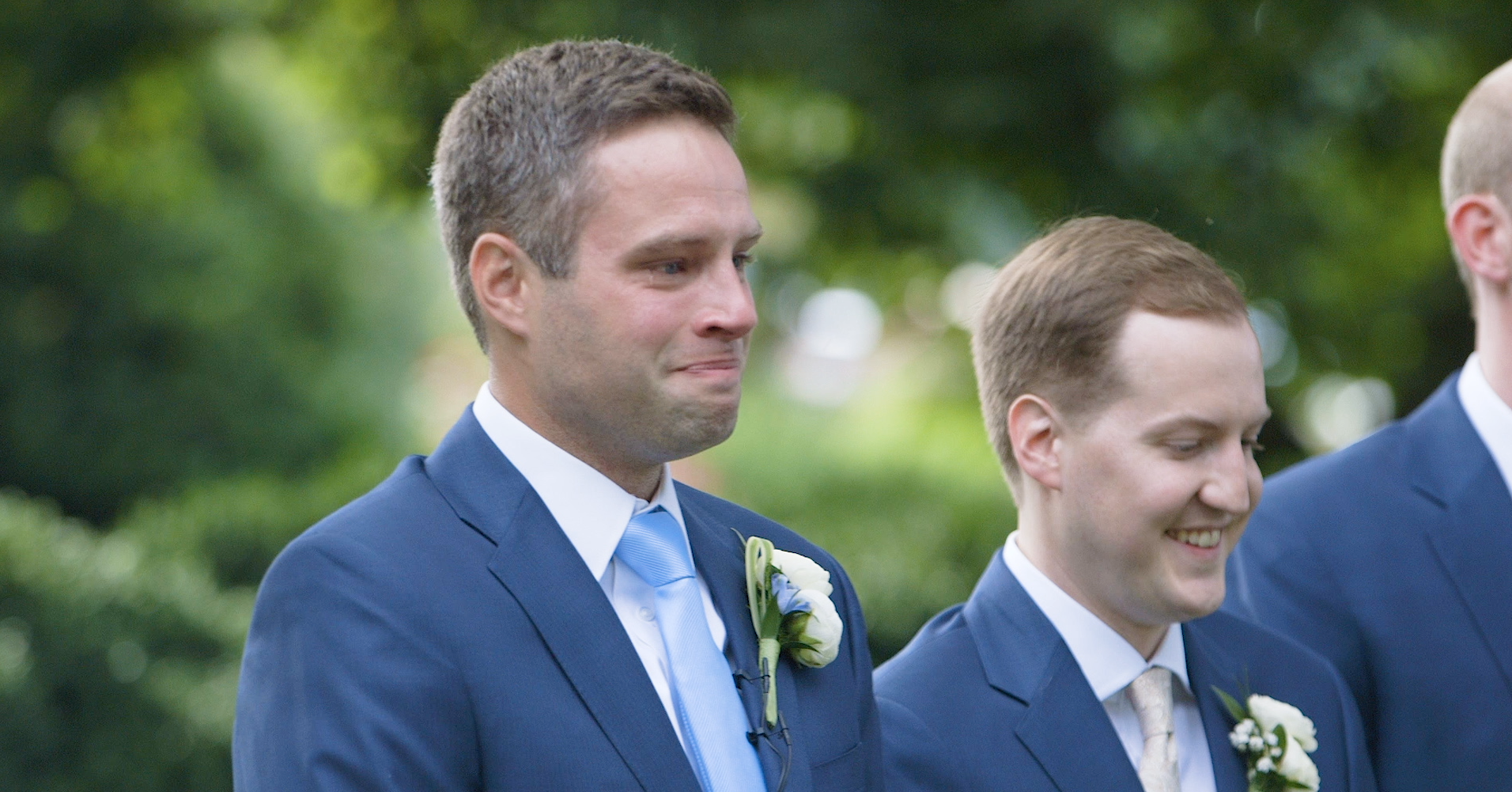 The groom stands crying tears of joy at the alter while his bride walks down the aisle.