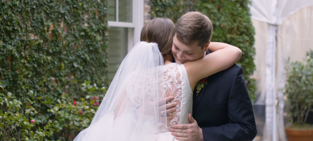 Groom hugs bride during the first look hire a wedding videographer