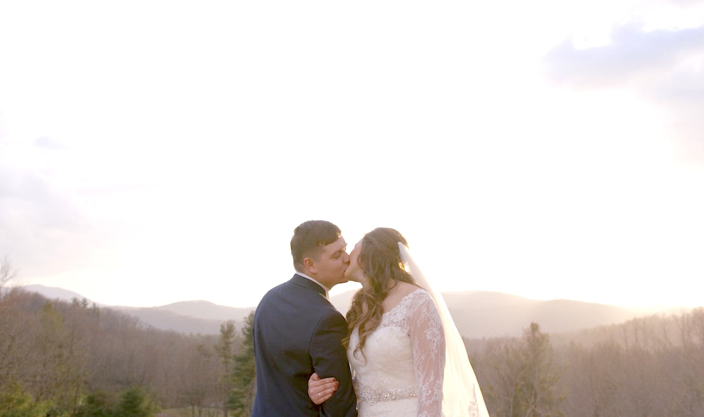 bride and groom kiss on top of a mountain
