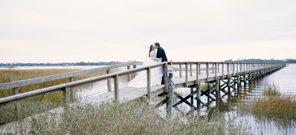 bride and groom stand on a dock at lowndes grove in charleston