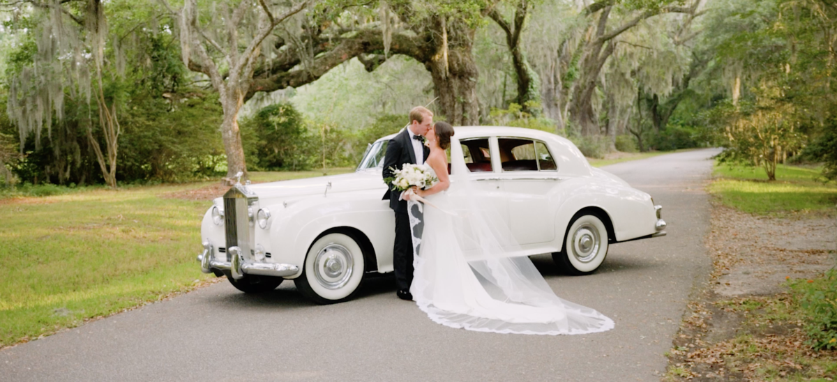 a bride and groom stand beside a vintage car at magnolia plantation